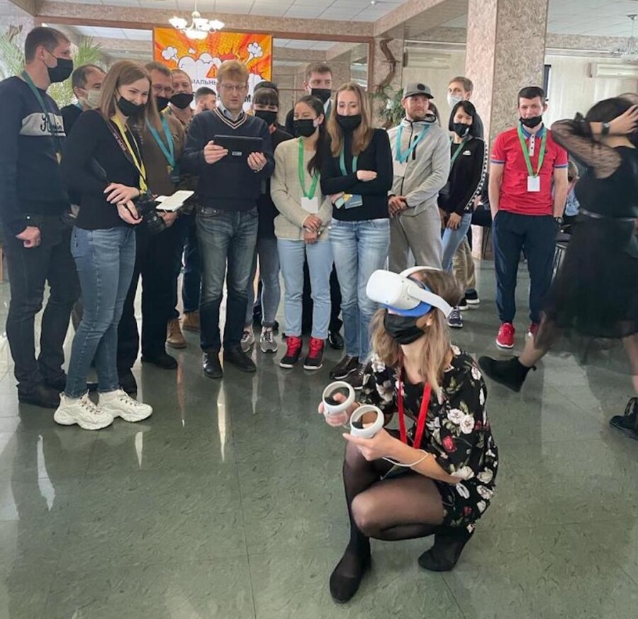 Участница в VR-шлеме проходит задание, коллеги наблюдают и обсуждают действия